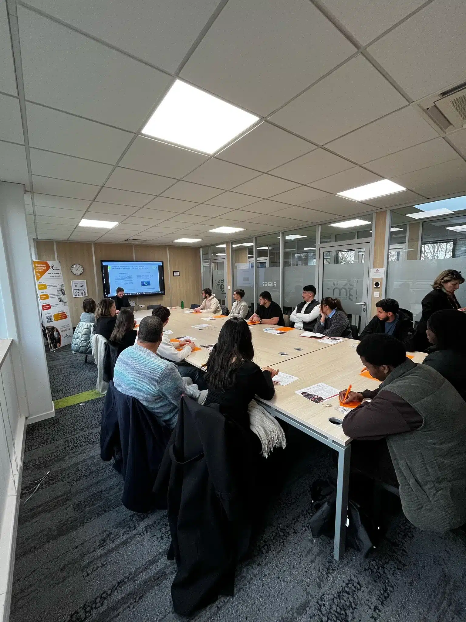 Groupe d'étudiants en BTS, licence ou master dans le haut-rhin attentifs lors d'une conférence métiers dans une salle de formation moderne, avec un intervenant projetant une présentation sur un écran.