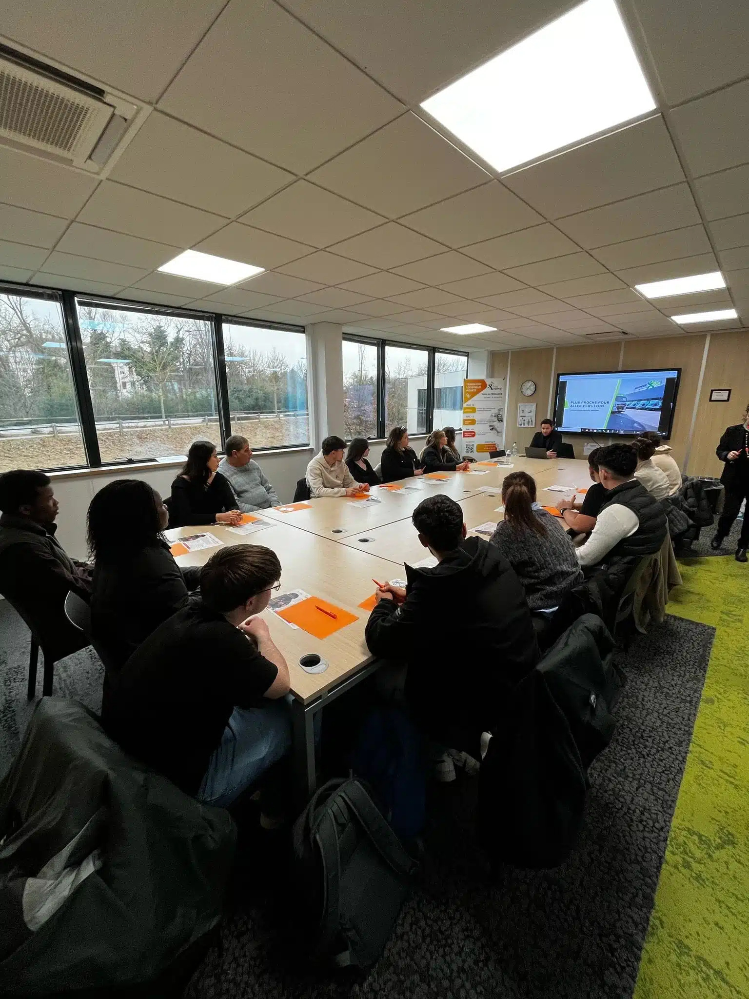 Groupe d'étudiants en BTS, licence ou master dans le haut-rhin attentifs lors d'une conférence métiers dans une salle de formation moderne, avec un intervenant projetant une présentation sur un écran.