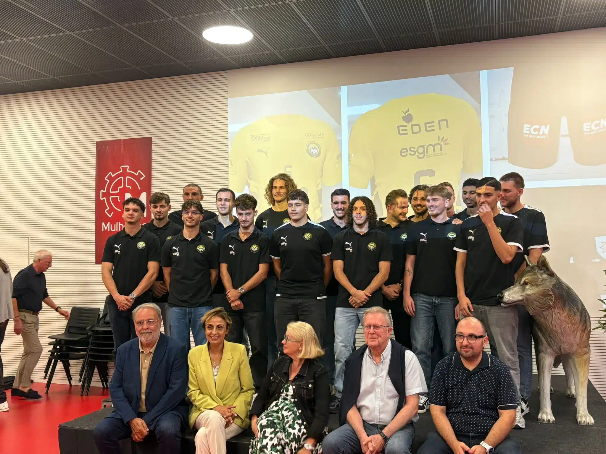 Joueurs de l'ASPTT Mulhouse Rixheim qui posent avec les élus de la ville devant la projection du nouveau maillot de l'équipe.