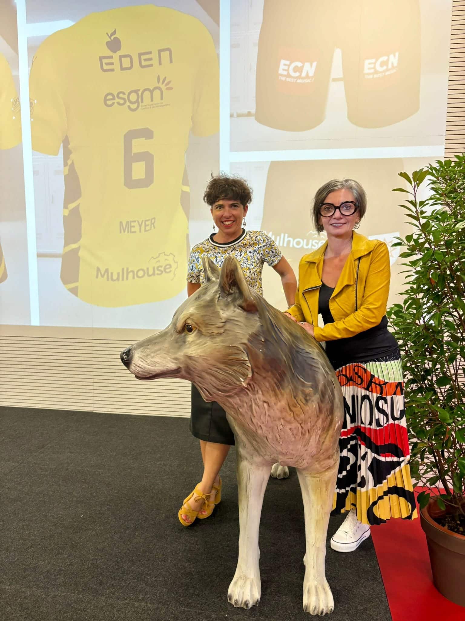 Aurélie Vervoort et Carine Walch, les deux directrices du Campus qui posent devant le nouveau maillot de l'ASPTT et derrière une statue de Loup, l'emblème du club !